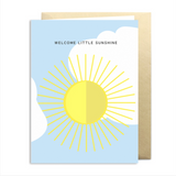 Greeting card with sun design and 'Welcome Little Sunshine' text on a light blue background.