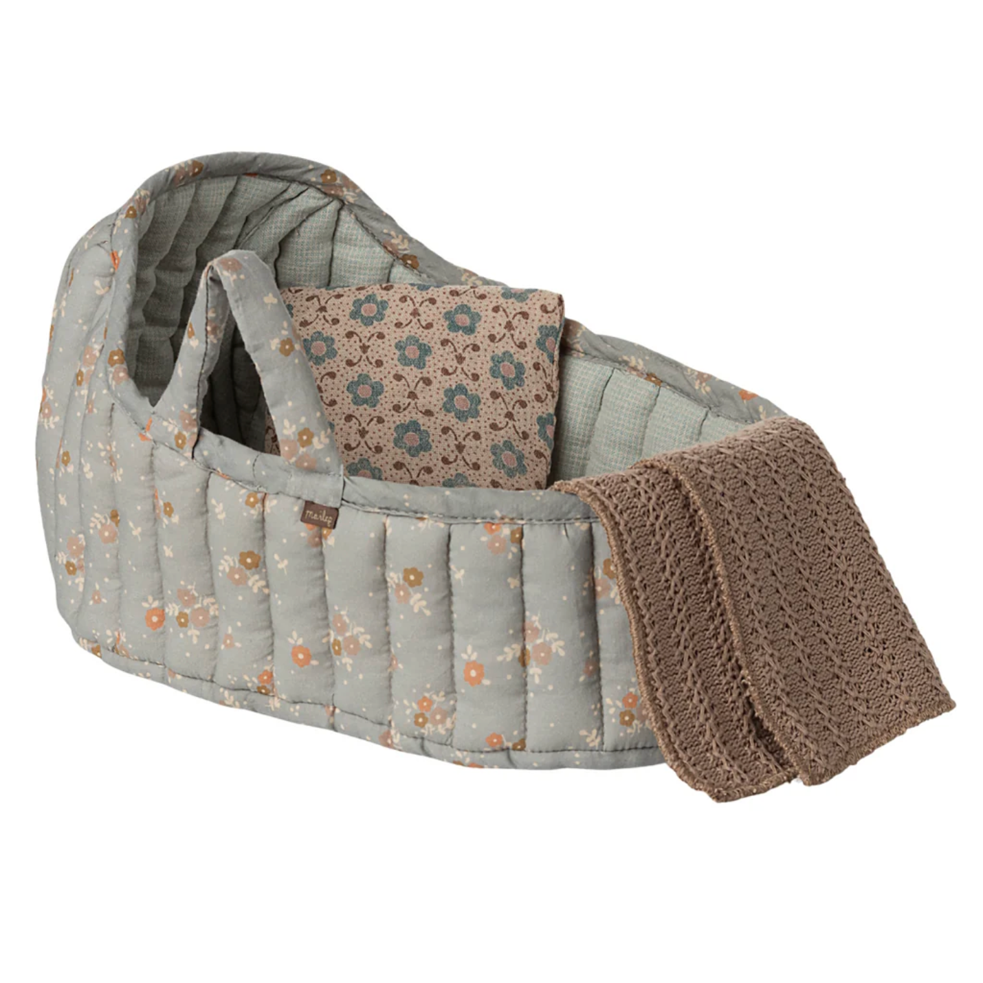 A quilted baby bassinet or carrier seat in a muted sage green floral print, shown with a patterned insert cushion and a folded brown knit blanket on a plain white background.
