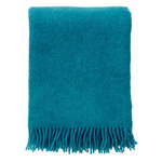 Teal blanket with fringes on a white background, displayed on a website for Klippan.