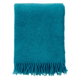 Teal blanket with fringes on a white background, displayed on a website for Klippan.