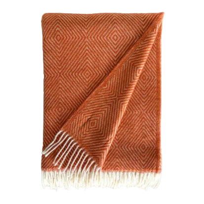 Orange woven blanket with white fringe on a light gray background